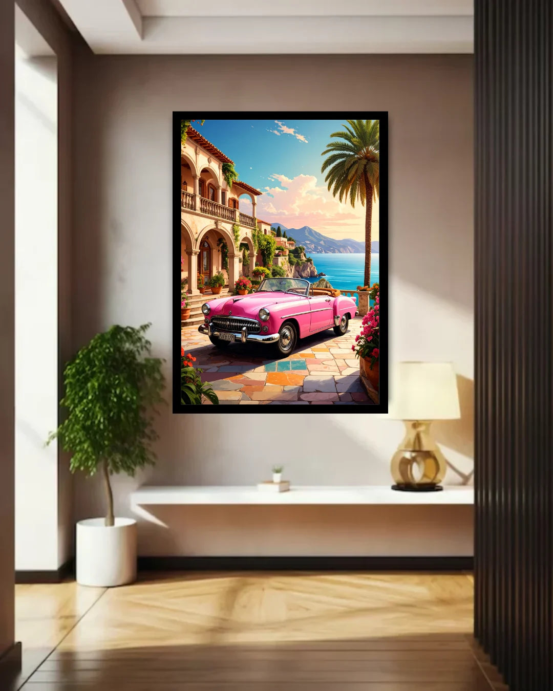 A framed wall art print depicting a bright pink convertible car parked by a coastal town with palm trees, mountains, and blue water, displayed in a modern interior hallway above a white bench.