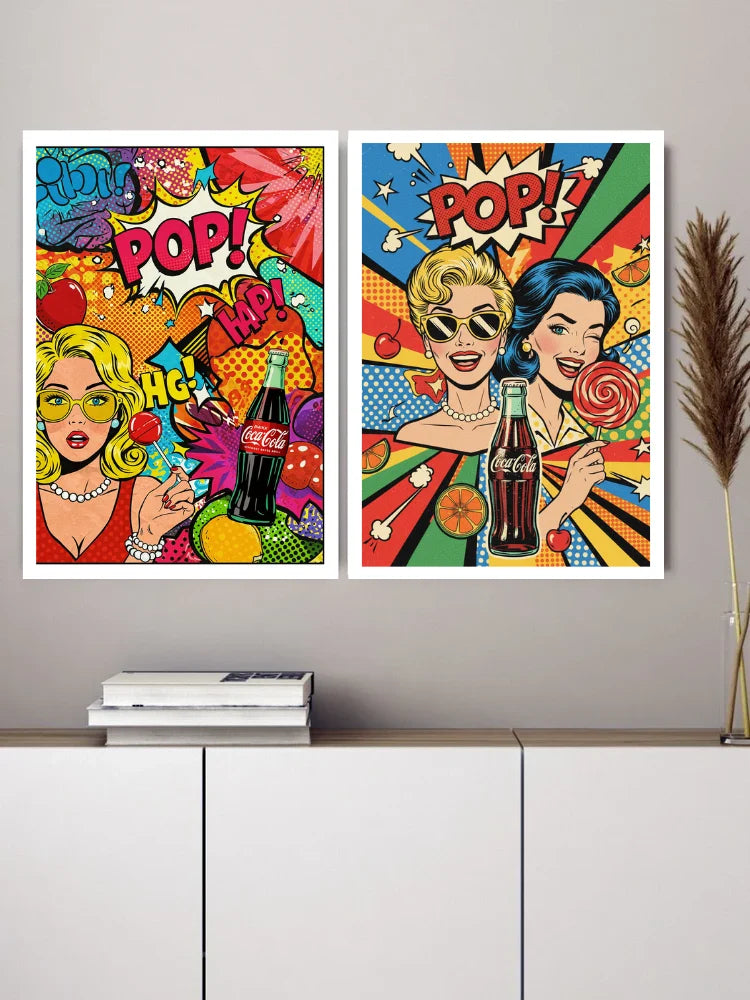 Two framed pop-art style wall prints with bold comic-style graphics and the word "POP!" displayed above a white cabinet against a light gray wall.