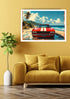 A framed wall art print showing a red classic car on a tropical beach, displayed above a mustard yellow sofa in a styled living room setting.