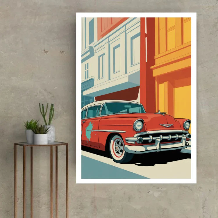A framed art print featuring a retro 1950s red classic car on a city street, displayed on a textured gray wall next to a small side table with potted plants.