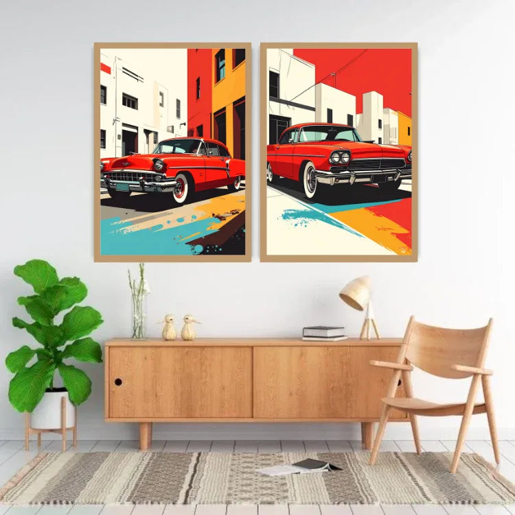 A pair of framed pop-art style wall prints depicting red classic cars in colorful urban street scenes, displayed above a light wood console table in a modern living room setting.