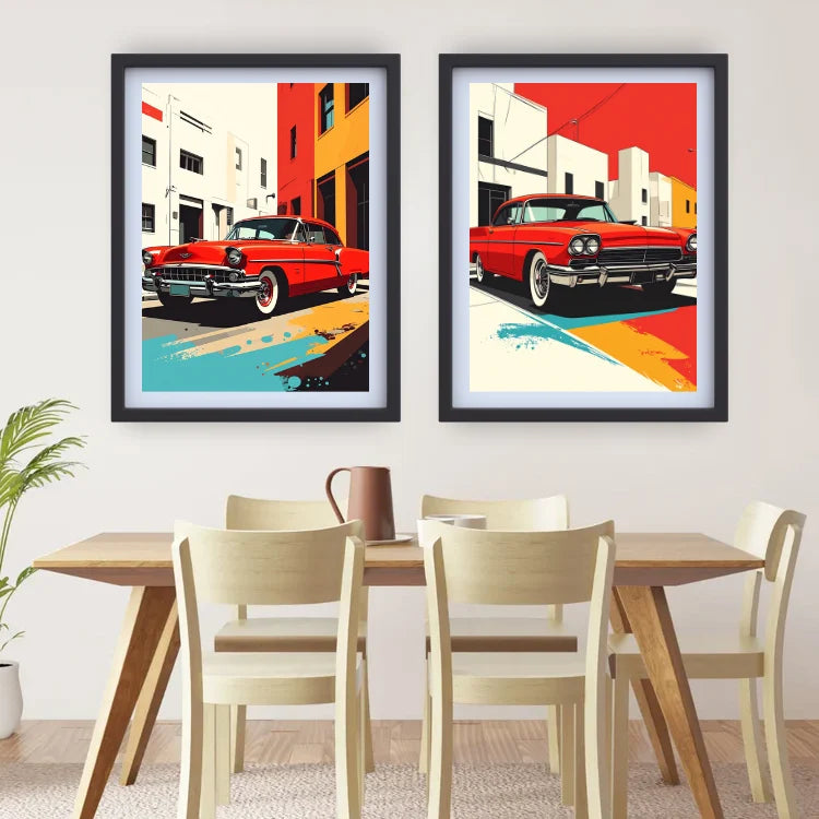 Two framed pop-art prints featuring red classic cars in stylized city street scenes, displayed side by side on a white wall above a wooden dining table and chairs.
