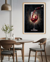 Framed artwork of red wine being poured into a glass above a dining table.