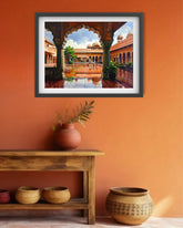 A framed art print depicting a traditional Indian courtyard with arches and a reflecting pool, displayed on an orange wall above a wooden shelf with decorative pottery.