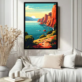 A framed vertical canvas print of a coastal landscape with orange cliffs, blue water, and a pale sun, displayed on a white paneled wall above a white sofa in a styled living room.
