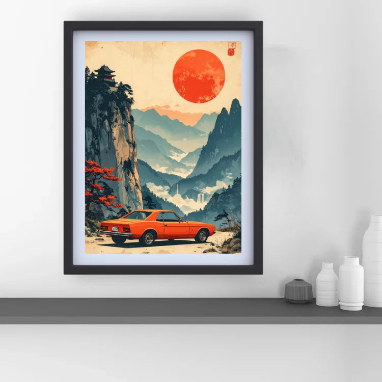 A framed art print featuring a retro orange muscle car in a stylized mountain landscape with a large red sun, displayed on a shelf against a white wall.