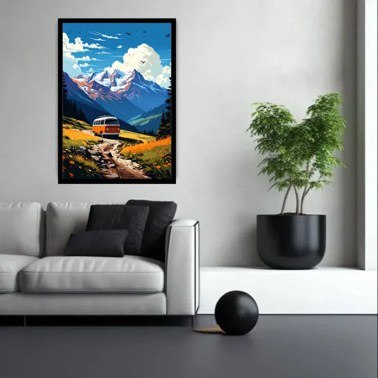 A framed vertical art print depicting a scenic mountain landscape with a vintage bus on a winding road, displayed on a light gray wall above a modern white sofa in a styled living room setting.