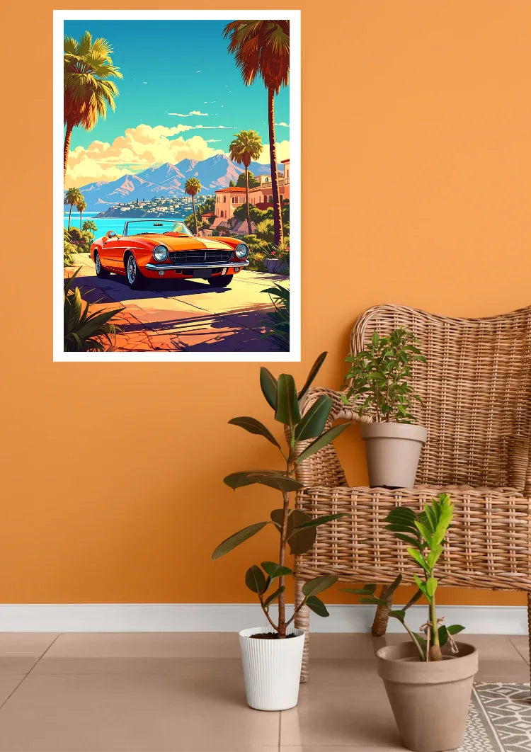 A framed art print featuring a retro orange classic car on a palm tree-lined coastal road, displayed on an orange wall above a wicker chair with potted plants.