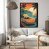 A framed vertical art print featuring a retro orange sports car on a tropical beach road at sunset, displayed on a light gray wall above a white sofa in a styled living room.