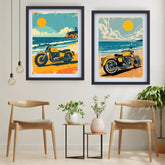 Two framed art prints featuring retro beach motorcycle illustrations hang on a light gray wall above two wooden chairs and small side tables in a styled interior room.