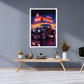 A framed vertical art print featuring a retro neon-lit hot rod car in front of a diner, displayed on a gray wall above a styled wooden console table in a modern room.
