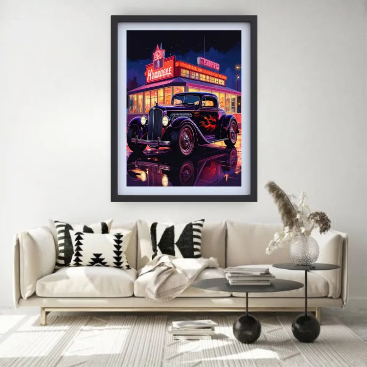 A framed wall art print depicting a neon-lit vintage car in front of a diner at night, displayed above a beige sofa in a modern living room setting.