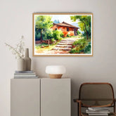 Framed landscape painting of a house with steps on a wall above a cabinet.