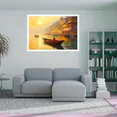 A framed wall art print depicting a warm sunset scene with small boats on water and glowing buildings, displayed above a light gray sofa in a modern living room setting.