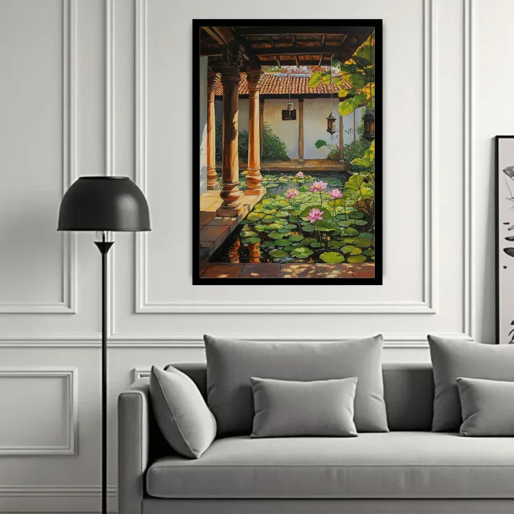 A framed vertical art print depicting a serene courtyard pond with lily pads and pink lotus flowers, hung on a white paneled wall above a gray sofa in a modern living room setting.