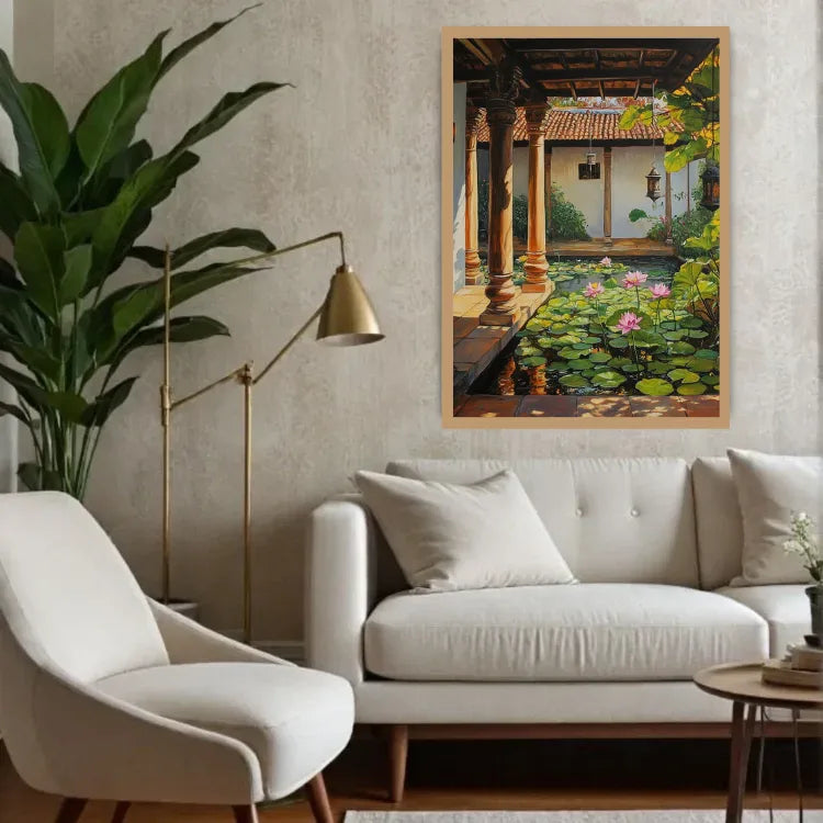 A framed vertical art print depicting a serene garden courtyard with a pond, lily pads, and a pavilion, styled on a textured beige wall above a white sofa in a modern living room setting.