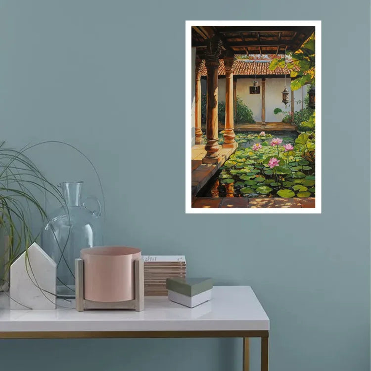 A framed art print depicting a serene courtyard pond with lily pads and pink flowers, displayed on a blue-gray wall above a styled white console table with decorative objects.