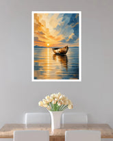 A framed vertical art print depicting a serene sunset over a calm lake with a small boat, displayed on a light gray wall above a dining table with white chairs and a vase of tulips.