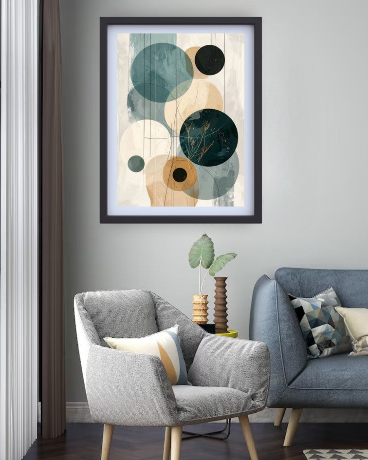 Framed abstract wall art with overlapping circles in teal, cream, tan, and black, displayed above a gray armchair in a modern living room setting.