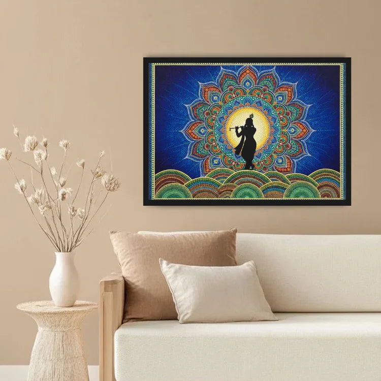 A framed wall art print featuring a colorful mandala design with a black silhouette of a flute player, displayed above a beige sofa in a styled living room setting.
