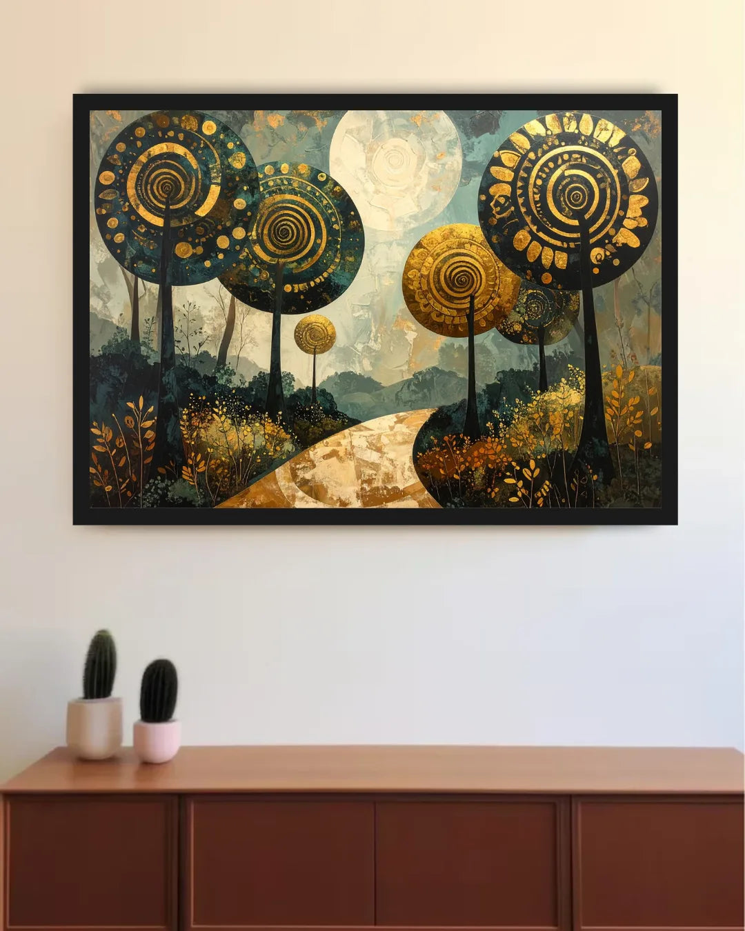 A framed abstract landscape art print featuring stylized trees with spiral patterns in gold, black, and blue tones, hanging on a white wall above a wooden cabinet with small potted cacti.