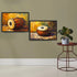 Two framed paintings of traditional Indian drums displayed on a beige wall above a white baseboard, with a small round side table and potted plant on the right.