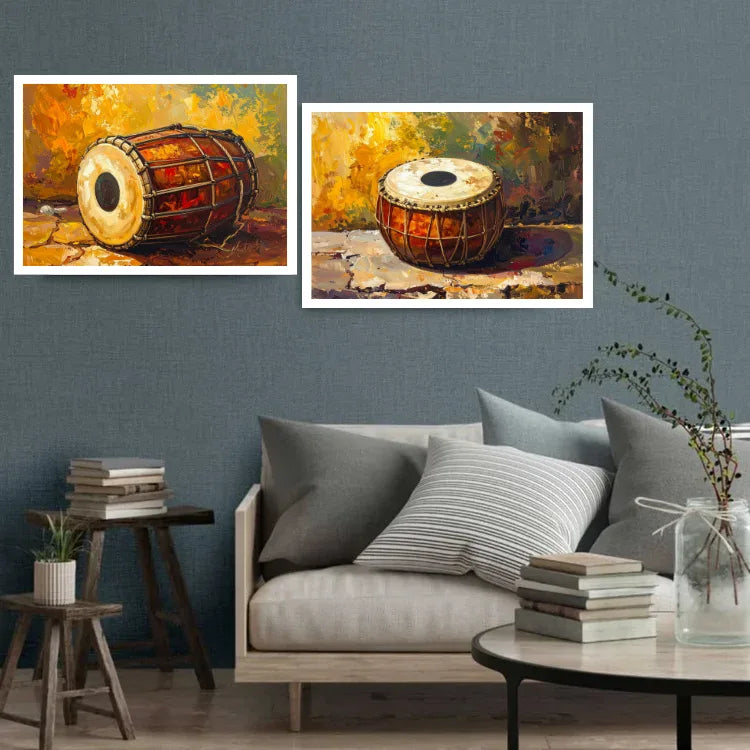 Two framed paintings of a traditional Indian drum (tabla) hanging on a textured blue-gray wall above a modern sofa in a styled living room setting.