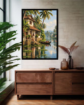 A framed wall art print depicting a tropical lakeside village with palm trees, a house, and a gondola, displayed above a wooden console in a styled interior room.
