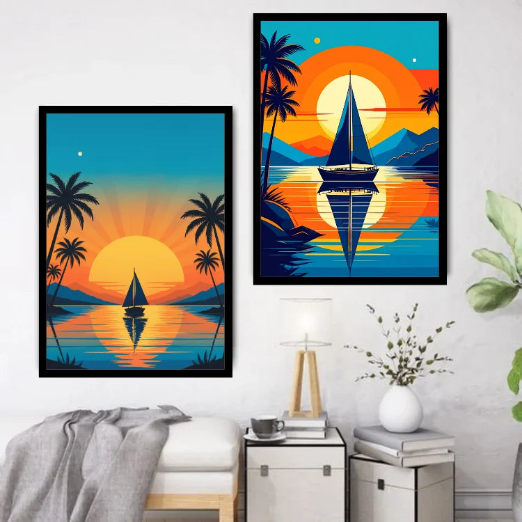 Two framed tropical sunset wall art prints hang on a white wall above a small side table with a lamp and vase. The left print shows a sailboat on calm water with palm trees and a large orange sun; the right print shows a larger sailboat centered over the water with palm trees, mountains, and a bright orange-to-blue sunset gradient.