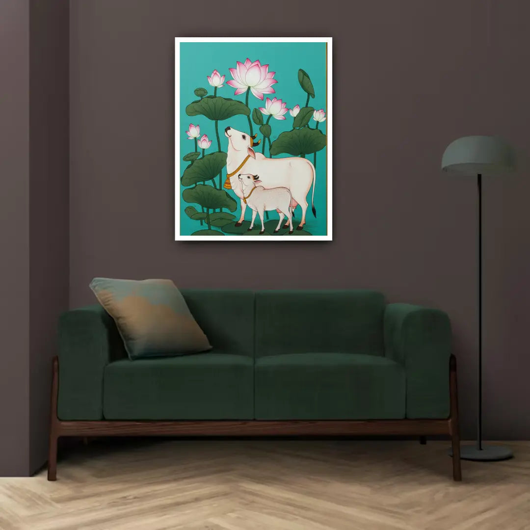 Framed artwork of two cows and lotus flowers on a wall above a green sofa.
