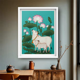 Framed artwork of a cow and calf among lotus flowers on a wall above a wooden table.