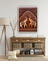 Framed artwork of two elephants under a tree on a wall above a wooden console table.