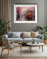A framed art print depicting a red streetcar traveling through a cherry blossom-lined street at dusk, displayed on a gray wall above a modern light gray sofa in a styled living room.